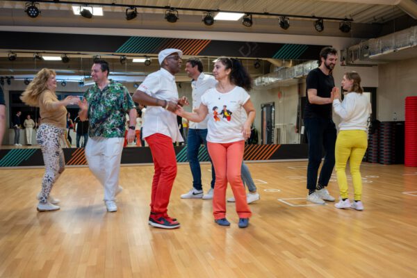 Osmay Silva und Manuela Rocha unterrichten Salsa in Ulm. In der Mitte führen die Lehrer den Salsa-Tanz vor. Dahinter sind drei Paare zu sehen, die Salsa tanzen lernen. Alles vor einem großen Spiegel in der Tanzschule Ritmo Latino®.