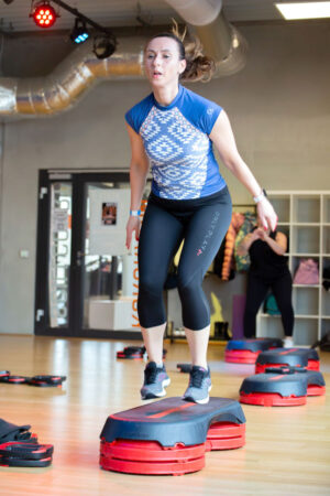Eine Frau in Sportkleidung springt während eines Fitnesskurses in der Tanzschule Ritmo Latino in Ulm auf einer Matte.