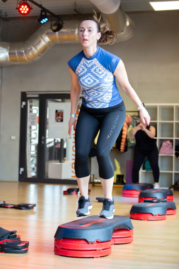 Eine Frau in Sportkleidung springt während eines Fitnesskurses in der Tanzschule Ritmo Latino in Ulm auf einer Matte.